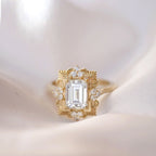 Detail macro view of a 3 carat emerald cut lab diamond ring in yellow gold highlighting the intricate milgrain and accent diamonds.