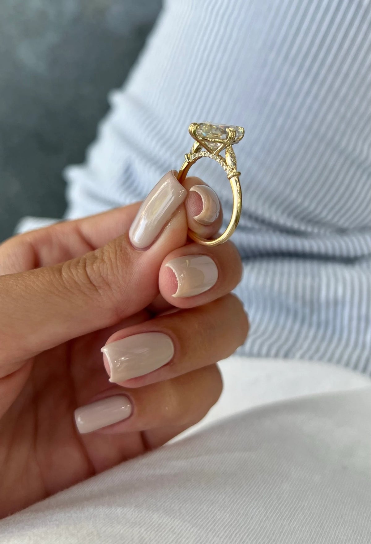 Close-up view of 4 carat oval lab diamond ring held in hand showcasing hidden diamond bridge design.