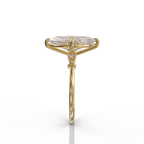 Direct side profile view of a yellow gold marquise lab diamond engagement ring displaying the bezel-set side accent stone.