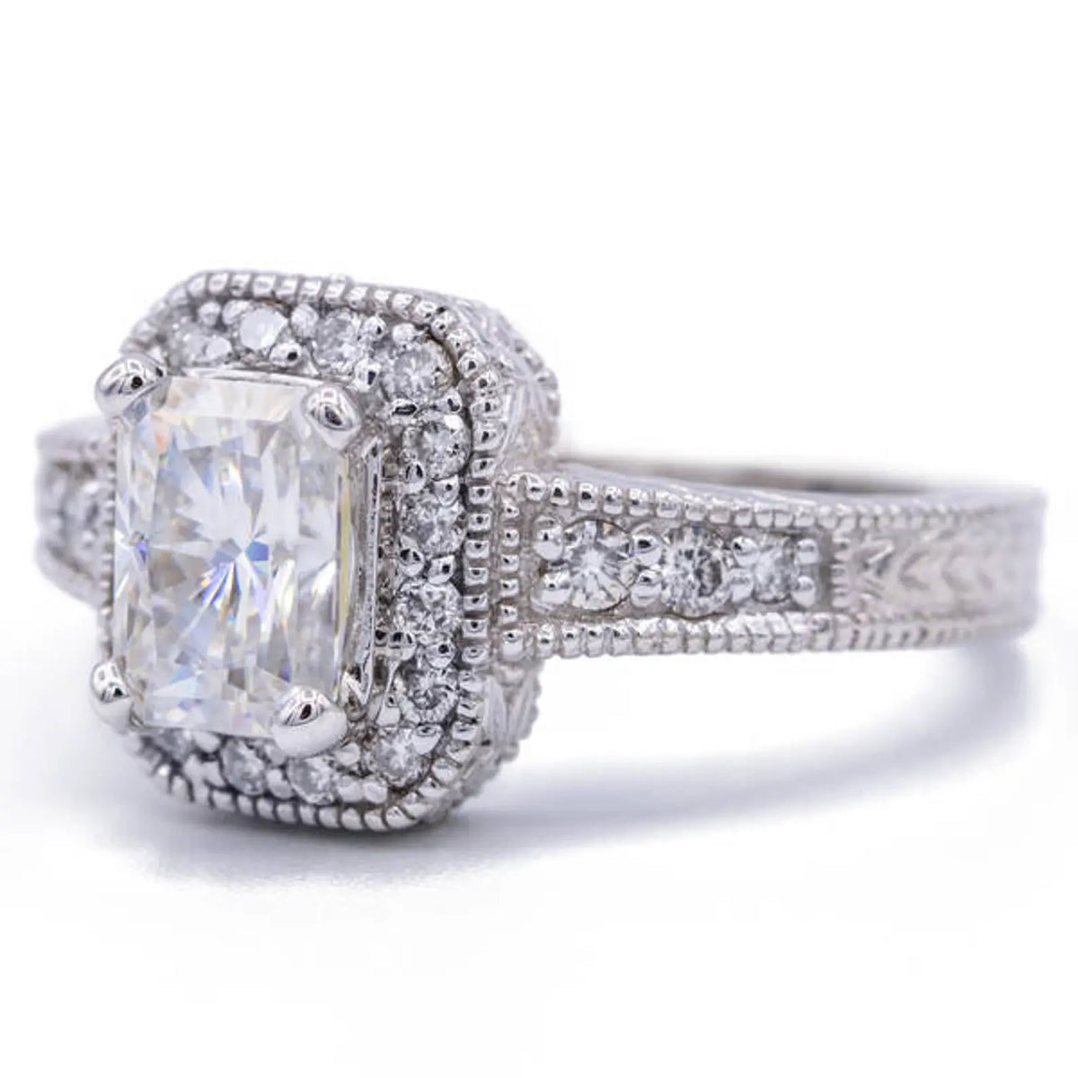 Three-quarter view of 3 carat radiant lab grown diamond ring displaying milgrain halo and hand-engraved side band details.