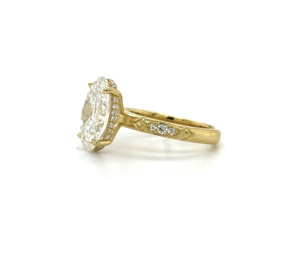 Side profile view of a 3 CT oval lab grown diamond engagement ring in yellow gold showing the hidden halo and engraved band.