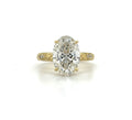 Top-down view of a 3 carat oval lab grown diamond engagement ring set in yellow gold with engraved side accents.