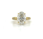 Top-down view of a 3 carat oval lab grown diamond engagement ring set in yellow gold with engraved side accents.
