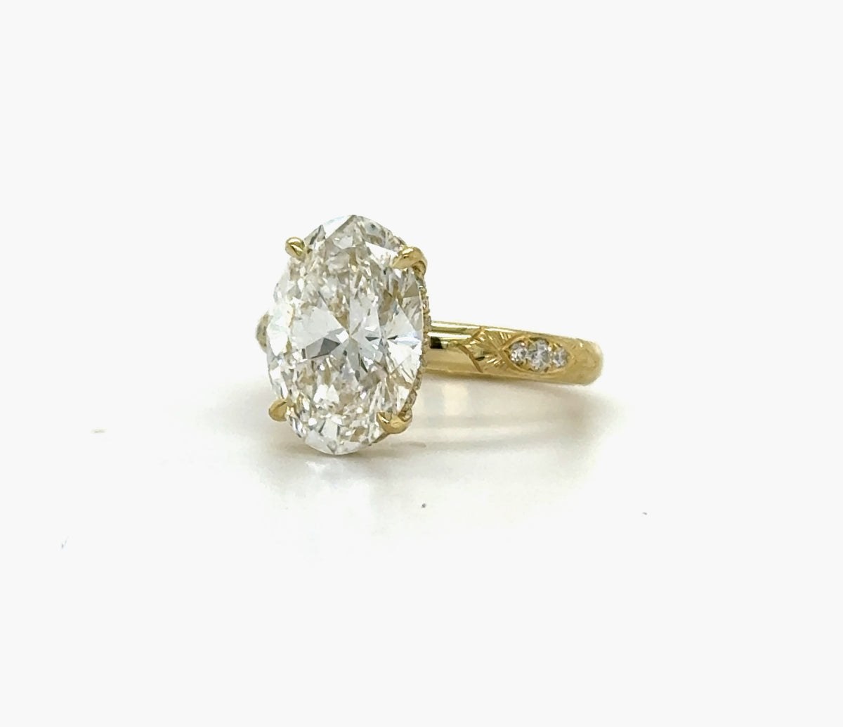 Three-quarter perspective view of a yellow gold 3 CT oval lab created diamond ring featuring side shoulder diamonds.