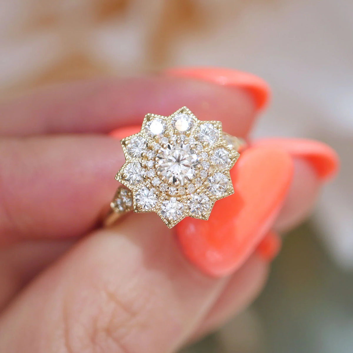 Close-up detail view of a 1.5 carat round lab diamond floral halo ring held between fingers highlighting the milgrain accent band.