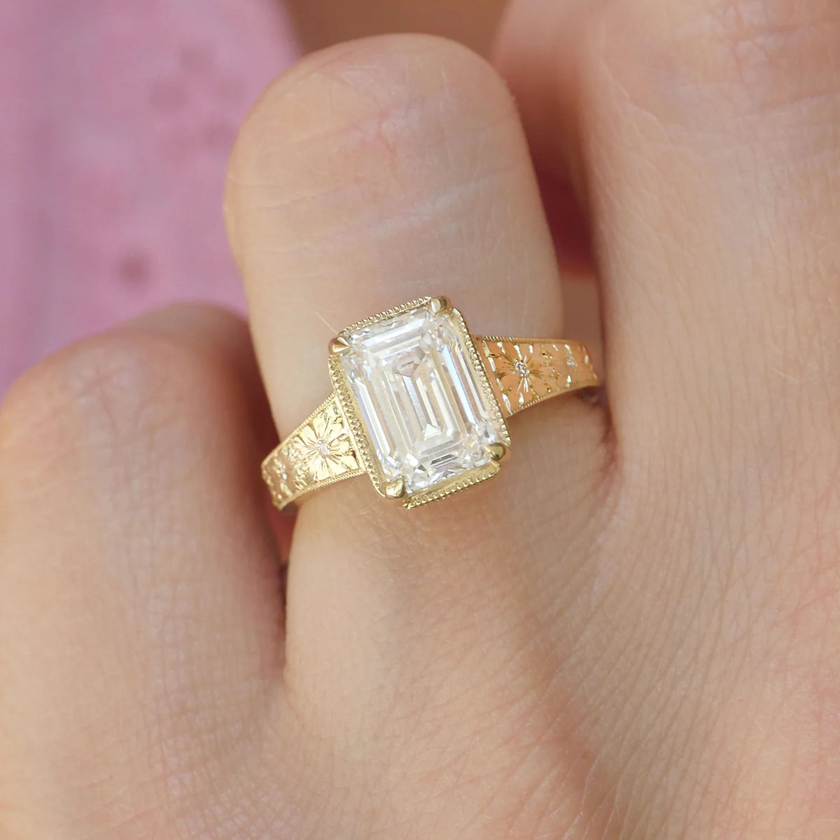 Close-up top view of a 3 carat emerald cut lab grown diamond ring with milgrain bezel setting and hand-engraved flower details.