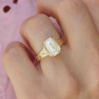 Angled top-down hand view showing a 3 carat emerald cut lab created diamond ring with vintage starburst floral engraving.