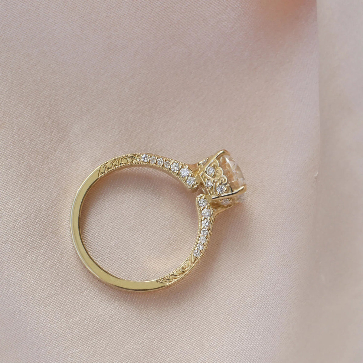 Side profile view of a yellow gold 2 CT round lab grown diamond engagement ring showing the filigree basket and engraved shank.