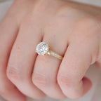 Close-up angled view on hand of a 2 CT round lab diamond engagement ring showing the cathedral setting and band engraving.