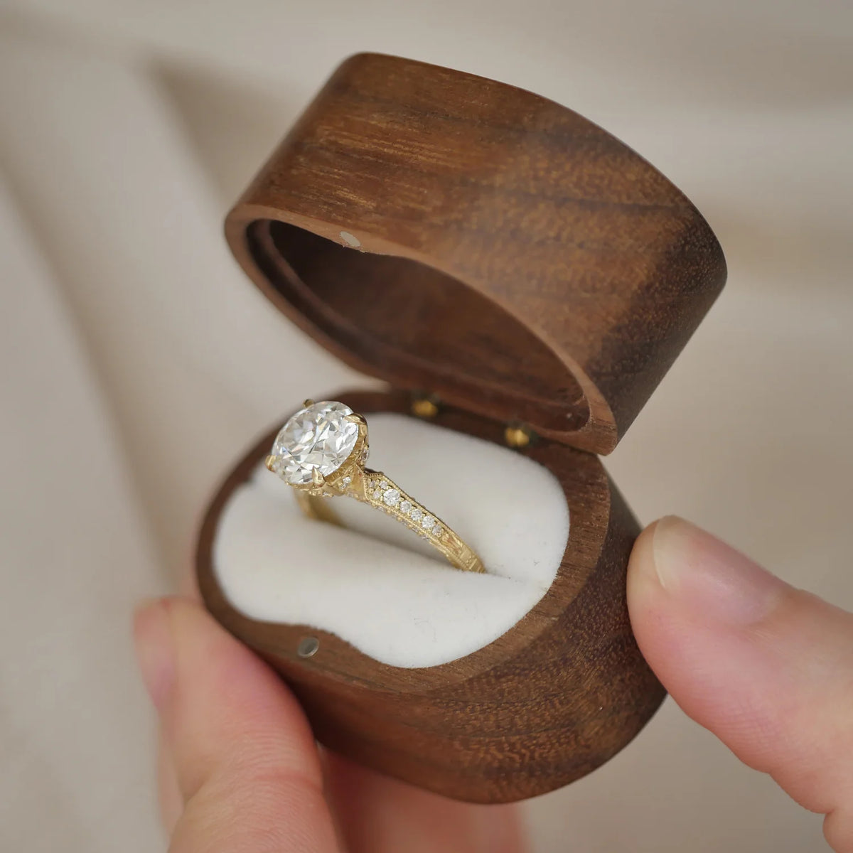 Angled profile view of a 2 CT round lab diamond vintage filigree ring inside an open wooden velvet ring box.