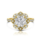 Top view of a 3 carat round brilliant lab diamond surrounded by a floral milgrain halo on a yellow gold pavé band.