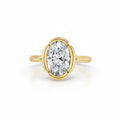 Top-down view of a 3 CT oval lab grown diamond solitaire ring encased in a contoured scalloped bezel frame with a smooth yellow gold band.