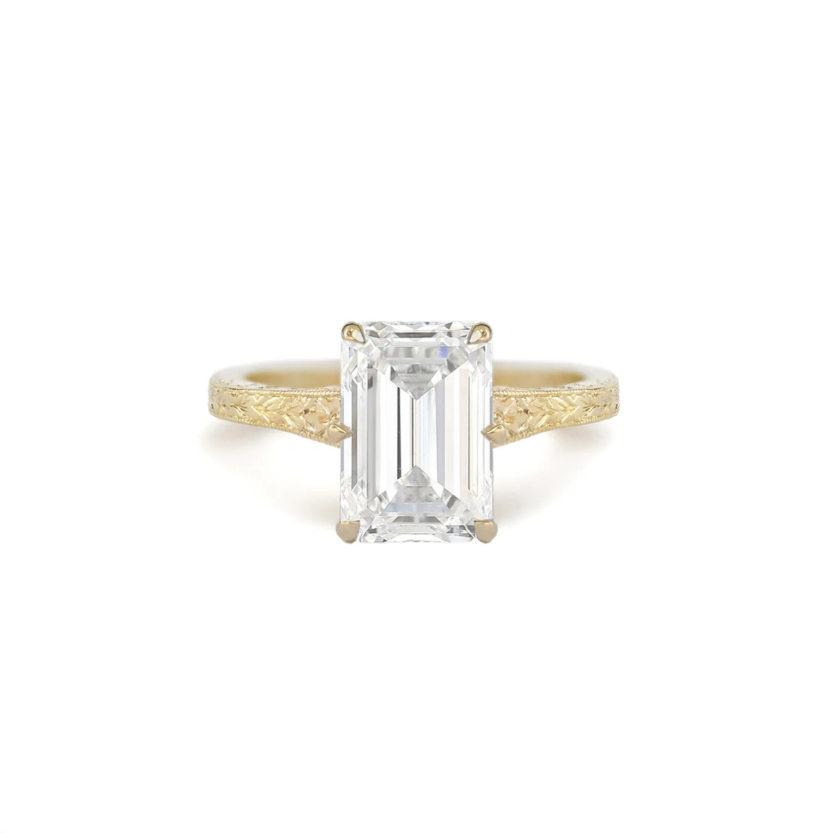 Front view of a 3 CT emerald cut lab grown diamond solitaire ring in 14K yellow gold with a hand-engraved botanical band.