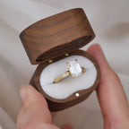 3 CT emerald cut lab grown diamond engagement ring with hand-engraved milgrain band and side accent diamonds displayed inside a wooden ring box.