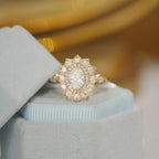 Front view of a 2 CT oval lab grown diamond ring with a scalloped sunburst halo displayed in a light blue box.