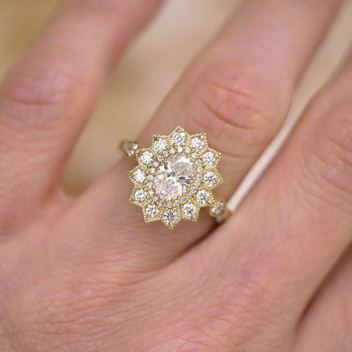 Close-up top view of a 2 CT oval lab diamond engagement ring with starburst double halo worn on finger.
