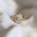 Top-down view showing a 3ct oval lab diamond encased in a detailed beaded milgrain bezel on a simple yellow gold band.