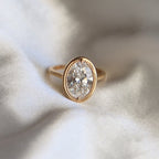 Top-down view showing a 3ct oval lab diamond encased in a detailed beaded milgrain bezel on a simple yellow gold band.