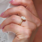 Angled view of a 2 CT oval lab grown diamond vintage engagement ring on a hand in yellow gold.