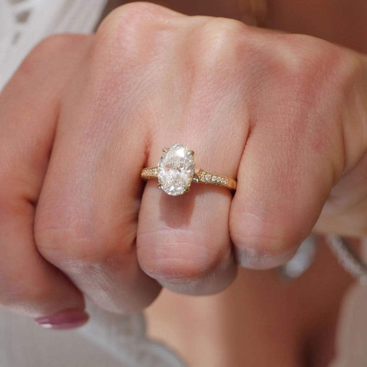 Top view of a 2 CT oval lab diamond ring with milgrain pavé band worn on finger.