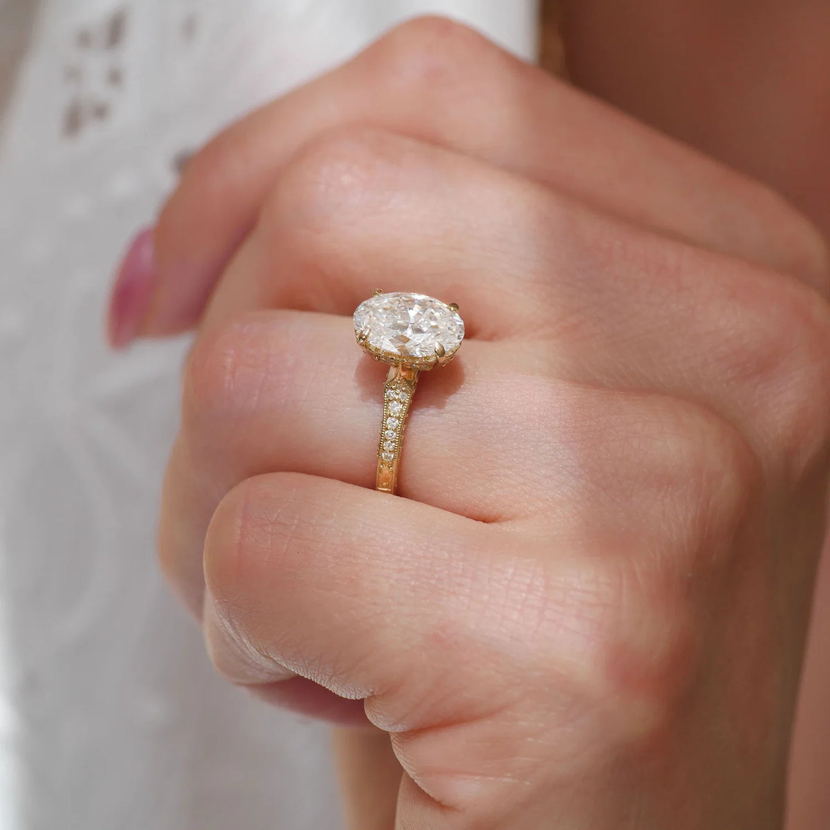Close-up of a 2 CT oval lab diamond engagement ring showing tapered milgrain shoulder accents.