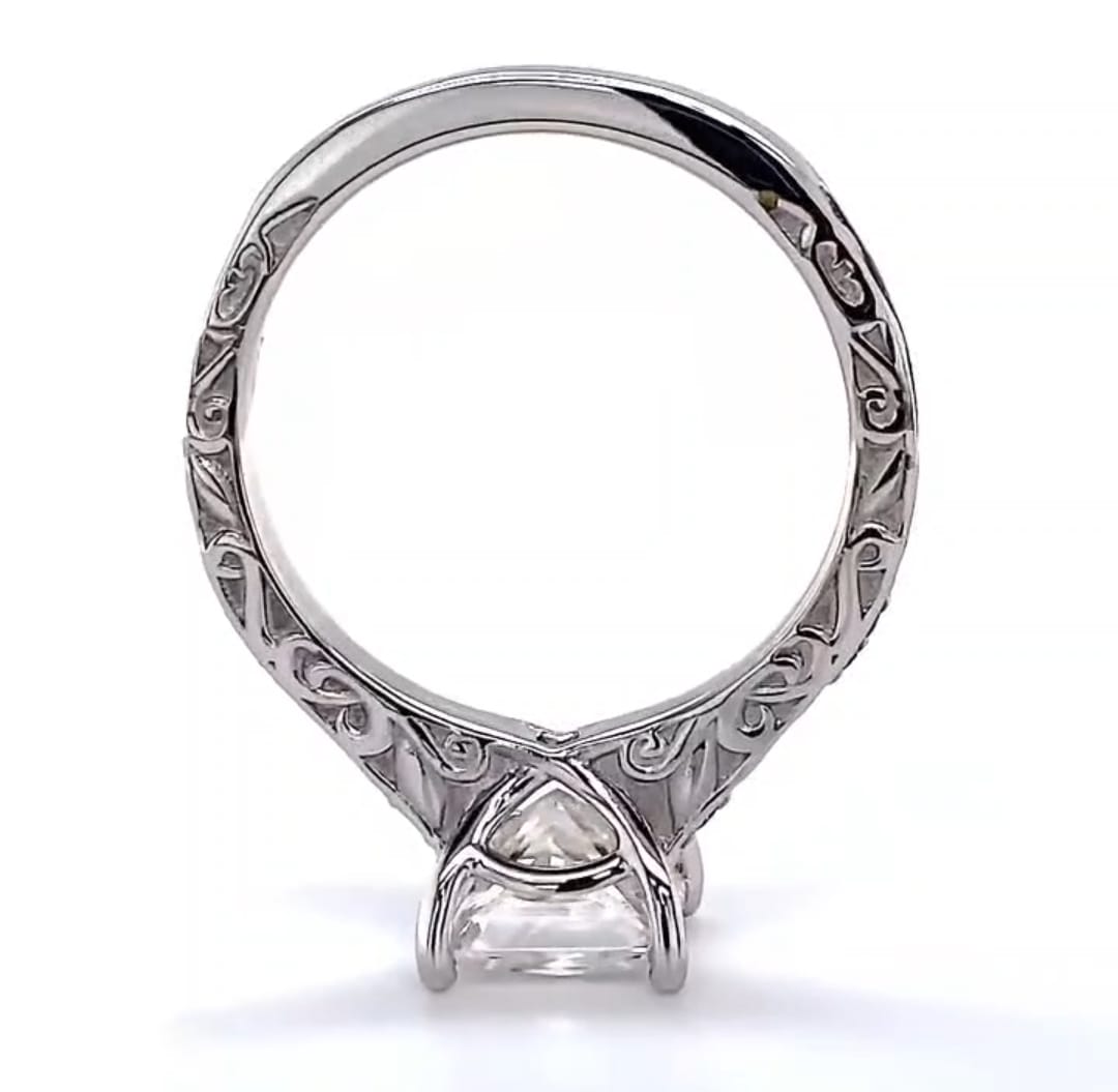 Bottom view of white gold engagement ring displaying the continuous carved scrollwork band and four-prong basket structure under the center diamond.