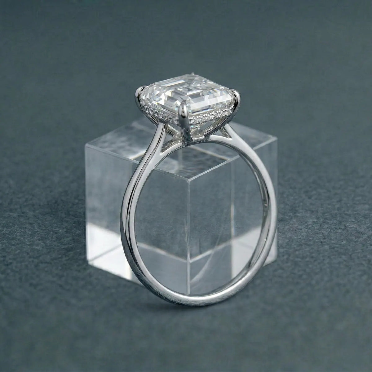 3 CT Asscher cut lab grown diamond solitaire engagement ring displayed on a clear glass block.