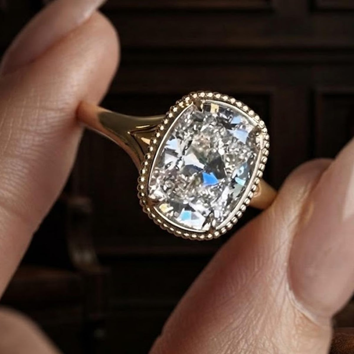 Angled profile of a cushion cut lab created diamond ring featuring a split-shank band and 4-prong beaded bezel setting.