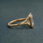 Side profile view of a 3 CT emerald cut lab grown diamond ring featuring a smooth yellow gold bezel setting and split-shoulder band.