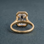 Underside view of a 3 carat emerald cut lab diamond ring displaying the open-back bezel setting and polished gold shank.