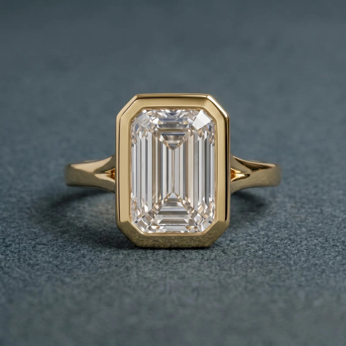 Direct top-down view highlighting the step-cut facets and protective yellow gold bezel frame of a 3 carat emerald lab diamond.