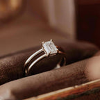 2 CT emerald cut lab grown diamond solitaire ring with double band setting resting in a ring box.