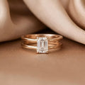 Close-up front view of 2 CT emerald cut lab grown diamond solitaire ring on champagne silk background.