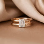 Close-up front view of 2 CT emerald cut lab grown diamond solitaire ring on champagne silk background.