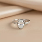 Front view of a 2 carat oval lab created diamond ring set in white gold bezel with milgrain edge.