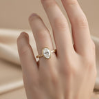 On-hand modeling view of a 2 CT oval lab grown diamond bezel ring in 14k yellow gold with engraved band.