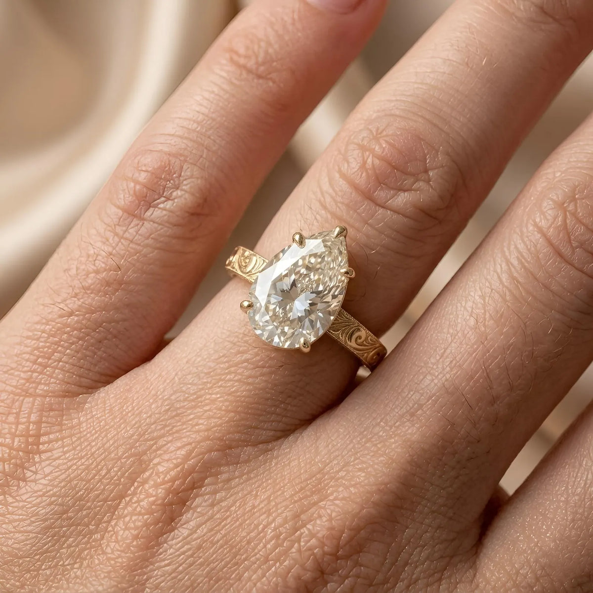 Direct top-down view of 3 carat pear cut lab created diamond ring featuring vintage floral engraved band.