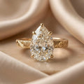 Studio front shot of a 3 CT pear cut lab grown diamond solitaire ring on champagne silk background.