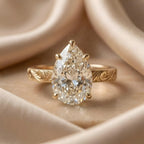Studio front shot of a 3 CT pear cut lab grown diamond solitaire ring on champagne silk background.