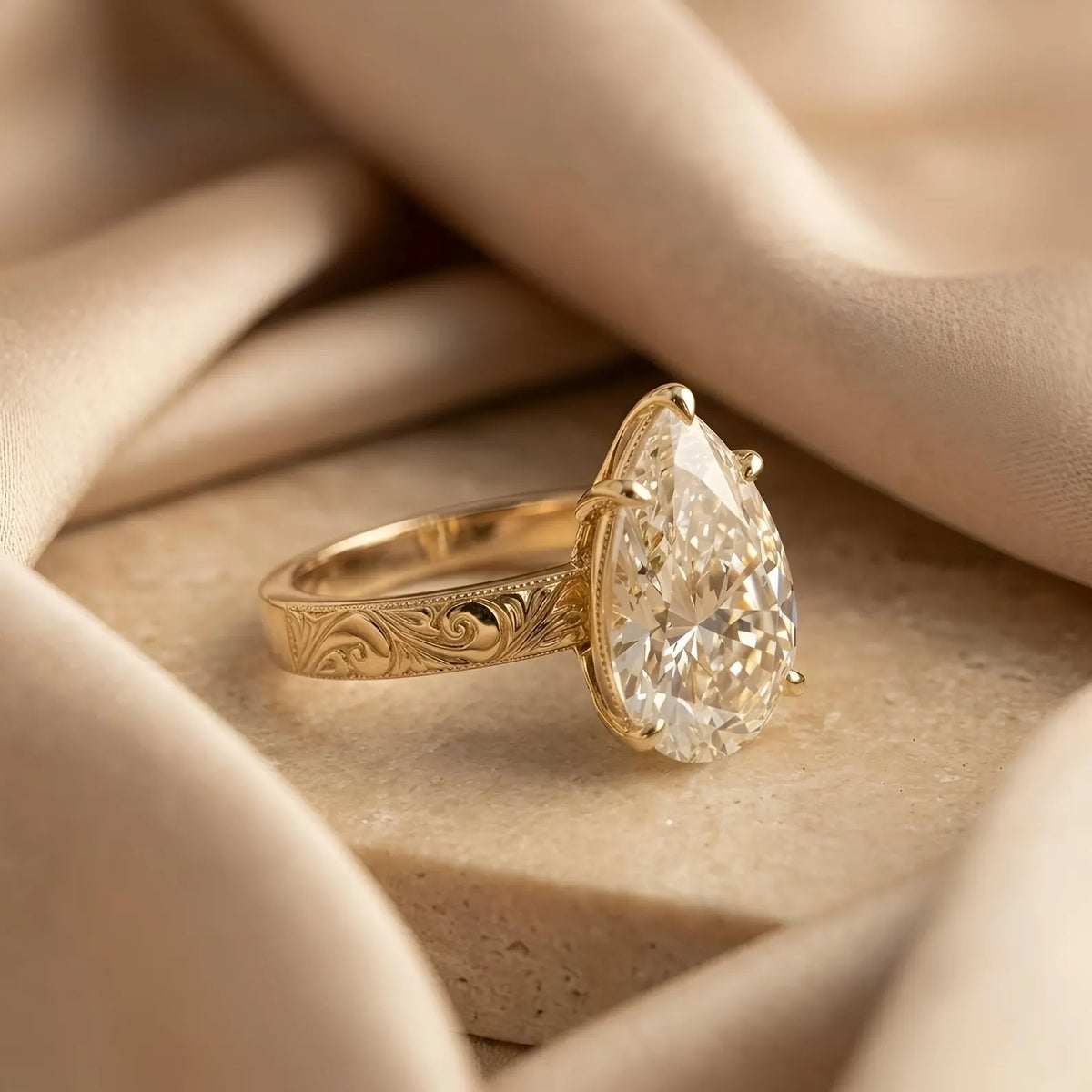 Side profile view highlighting hand-carved scrollwork and milgrain border on yellow gold pear ring.