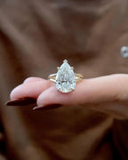 Close-up view of a 4 carat pear lab created diamond sitting on fingers showing claw prongs and split band.
