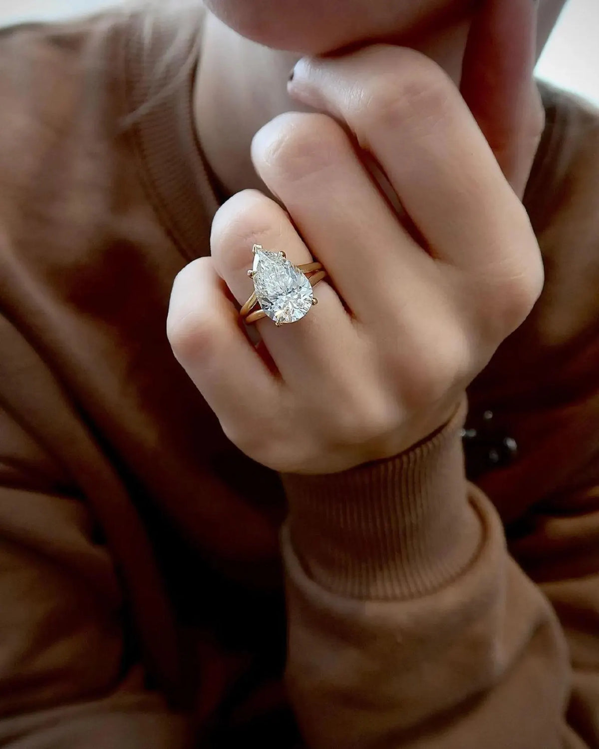 Full hand pose modeling a 4 carat pear lab grown diamond ring in yellow gold setting.