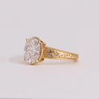 Side profile shot showcasing 4-prong setting, milgrain rim, and detailed floral scrollwork engraving on yellow gold band.