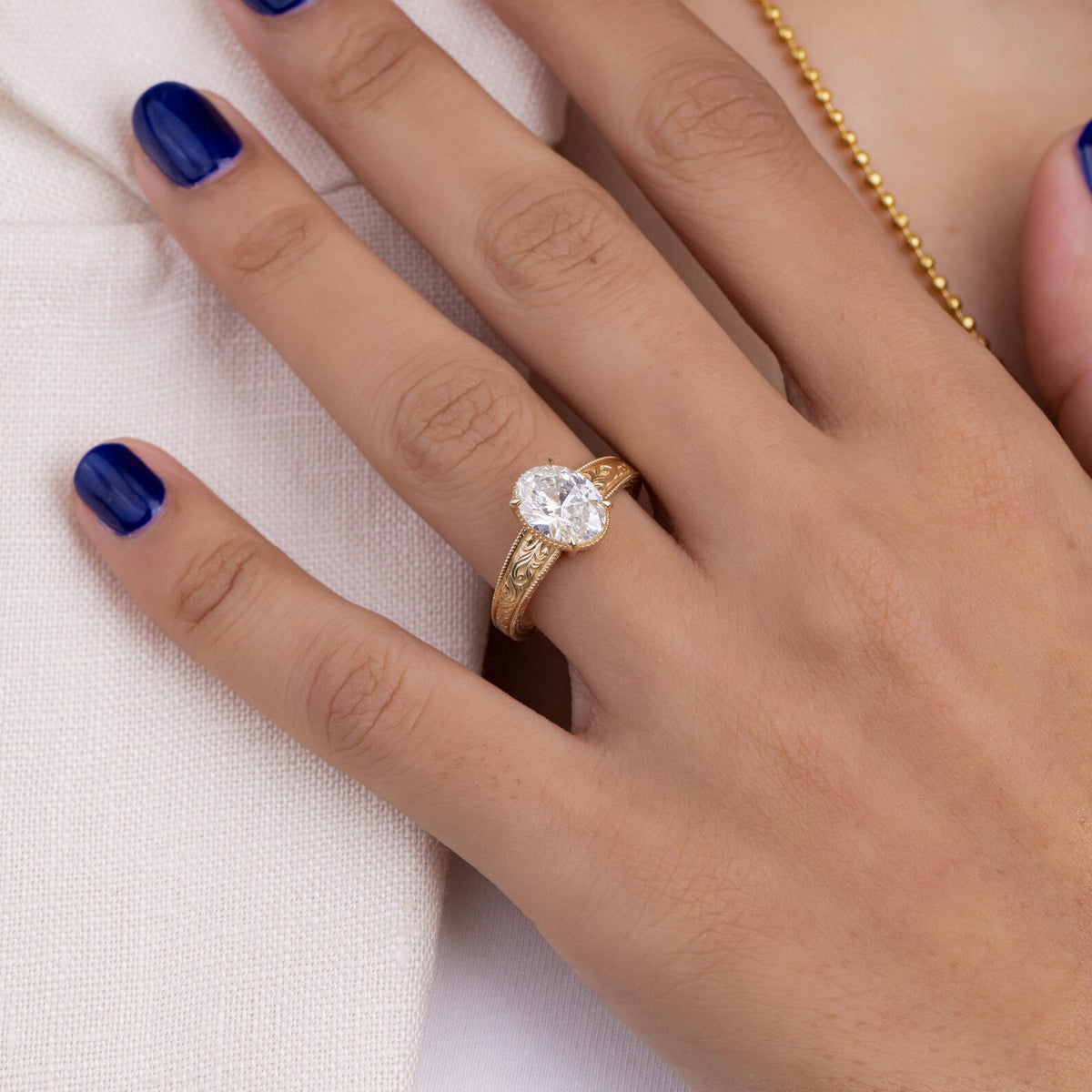 Top-down hand view of a 2 carat oval lab grown diamond engagement ring in 14K yellow gold.