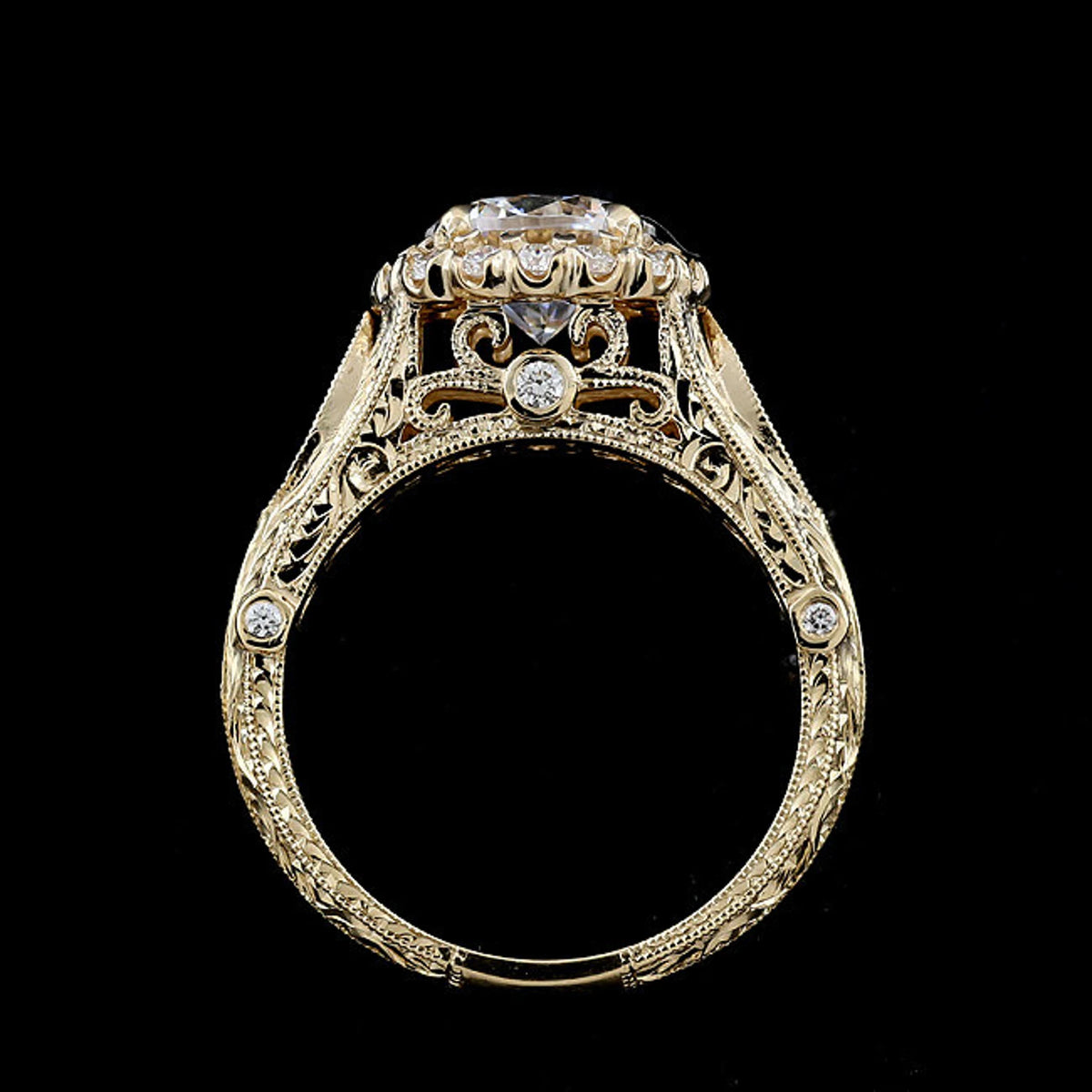 An ornate yellow gold filigree ring with a large round-cut center stone and smaller accent stones, shown against a solid black background.
