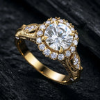 A gold ring with a large round clear center stone and multiple surrounding clear accent stones, photographed close up on a dark textured surface.