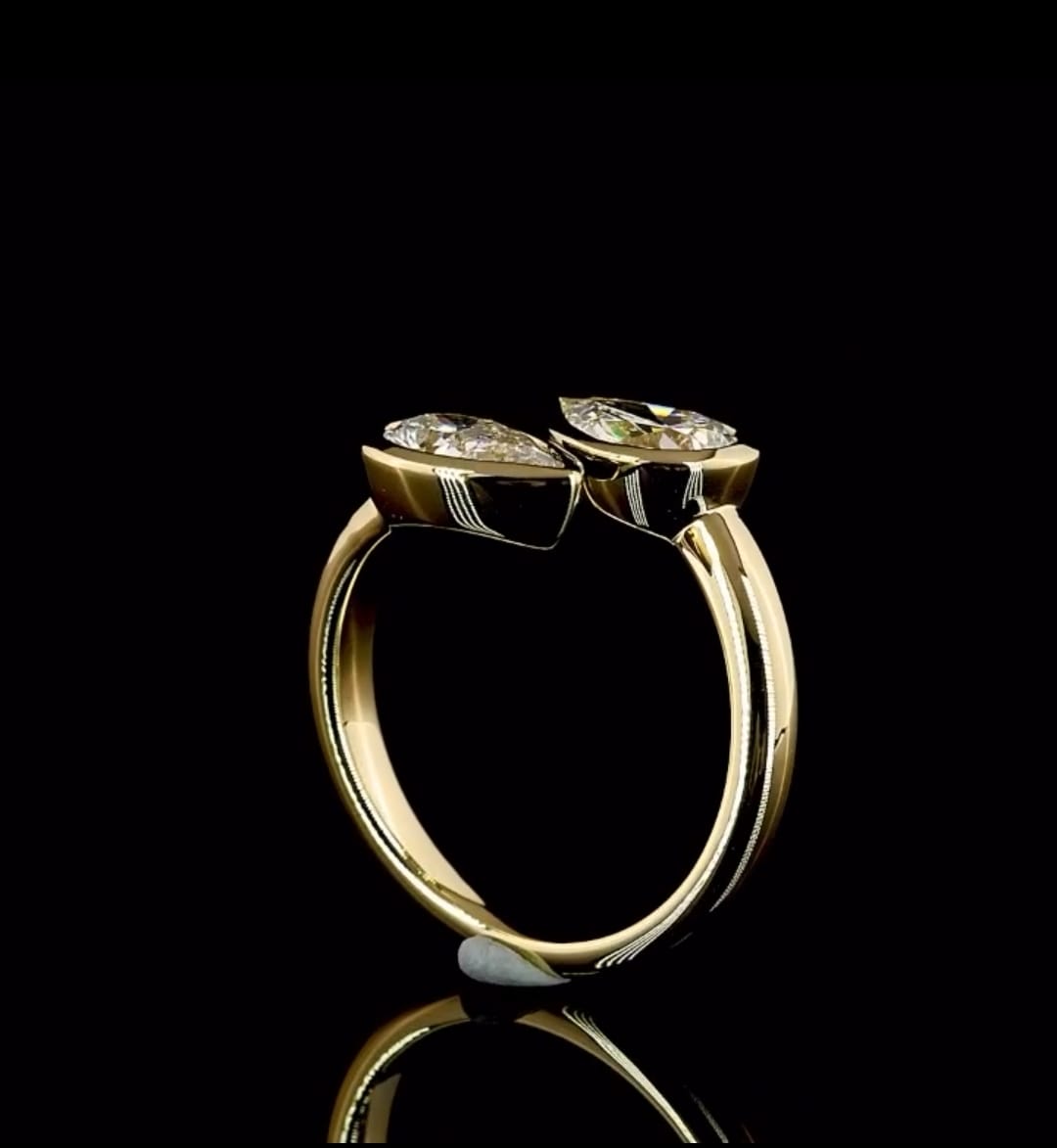 Side profile view of a yellow gold open cuff bypass ring with two raised bezel-set pear lab diamonds.