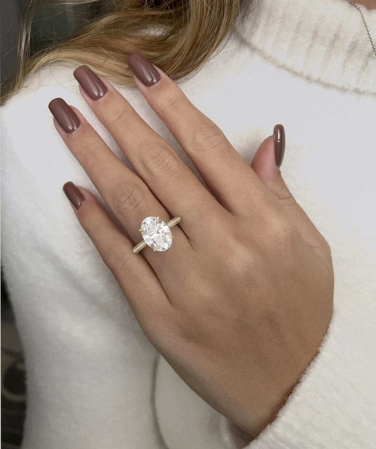 Lifestyle shot of a model wearing the 5 carat oval diamond ring against a white sweater.