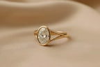side-profile-view-of-oval-cut-lab-diamond-bezel-ring-on-silk-background