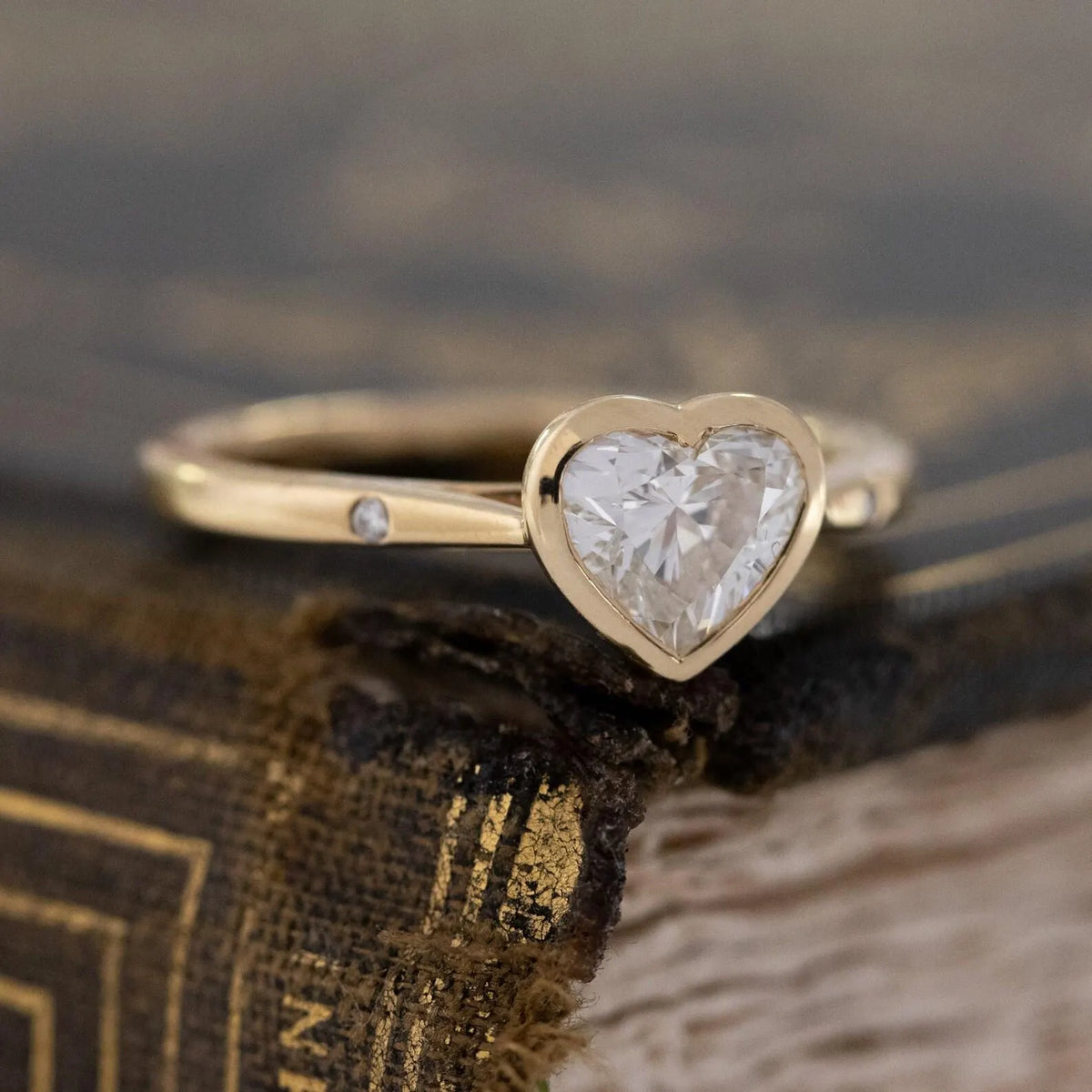 close-up-view-of-2ct-heart-lab-grown-diamond-bezel-ring-on-vintage-book